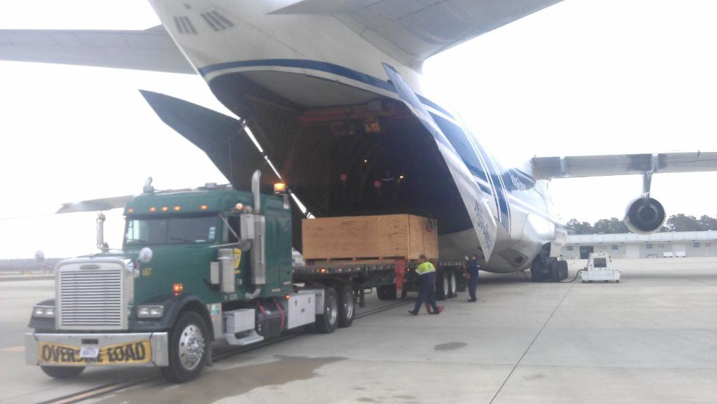Palletized green Freightliner delivering crated cargo directly to a cargo aircraft on the tarmac