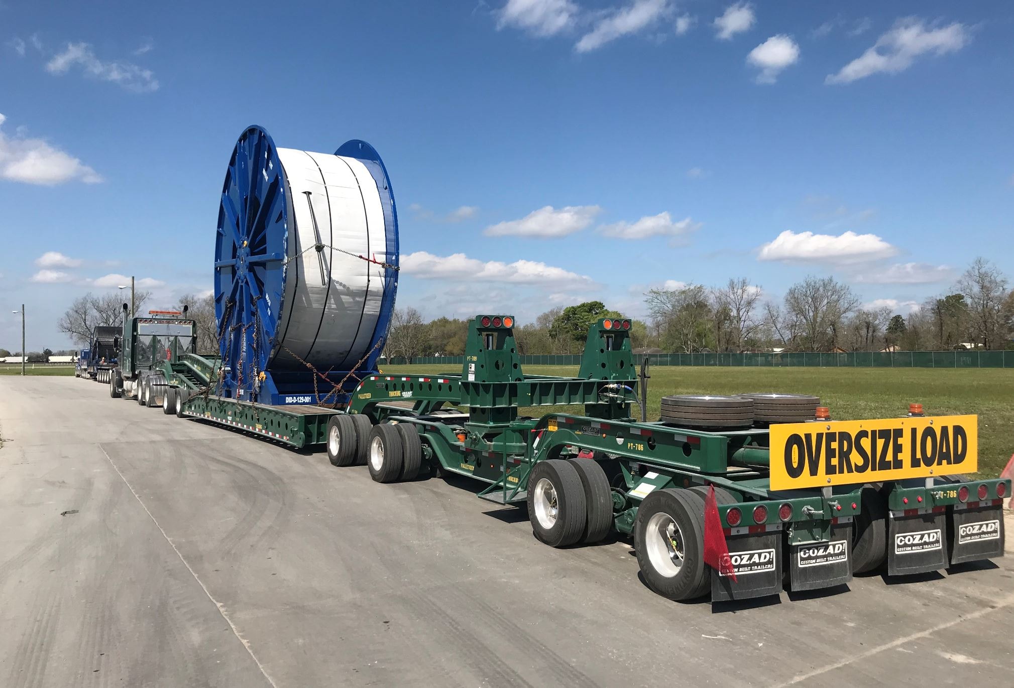 Palletized oversized cable spool on Cozad multi-axle lowboy with oversize load sign
