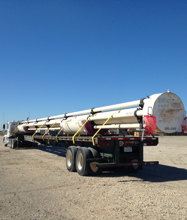 Palletized flatbed hauling oversized round industrial tank vessel on stretch trailer in West Texas