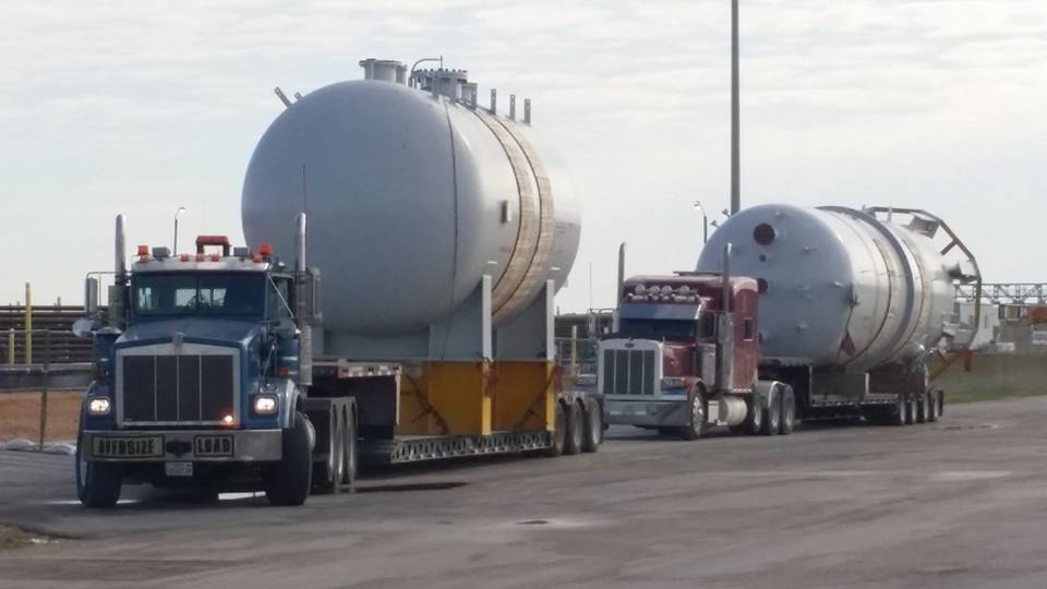 Two Palletized oversize load trucks hauling large industrial pressure vessels in convoy